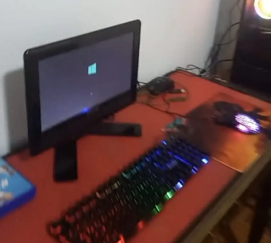 O PC ligado pela primeira vez: o monitor mostra o logo do Windows, o teclado e o mouse estão iluminados e o gabinete aceso ao fundo.